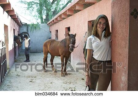 Picture - Woman smiling at horse stables on ranch. Fotosearch