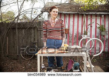 Stock Photo - Woman standing at table in backyard. Fotosearch