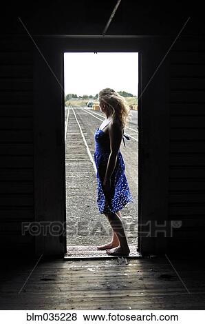 Stock Photo - Woman standing in doorway of train in train yard. Fotosearch