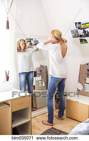 Woman styling her hair in mirror View Large Photo Image Stock Image - Woman styling her hair in mirror. Fotosearch