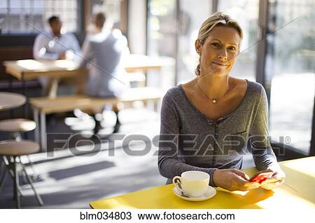 Stock Image - Woman using cell phone in cafe. Fotosearch