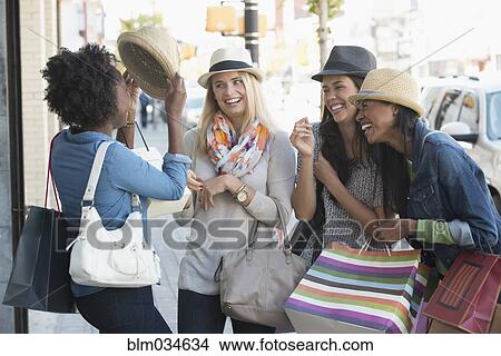 Picture - Women playing with hats on city sidewalk. Fotosearch