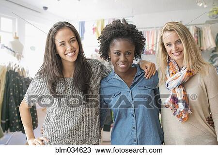 Stock Image - Women smiling in clothing store. Fotosearch