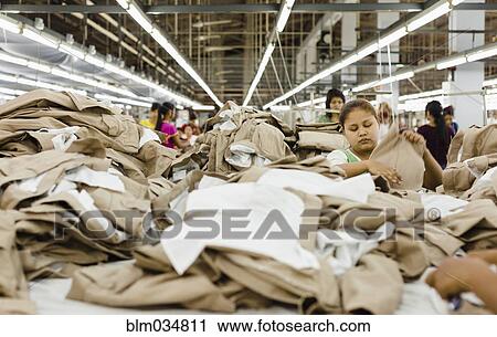 Stock Image - Workers folding clothing in garment factory. Fotosearch