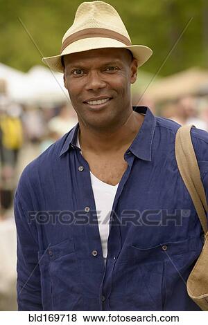 Stock Photo - African American man wearing hat and tote bag. Fotosearch