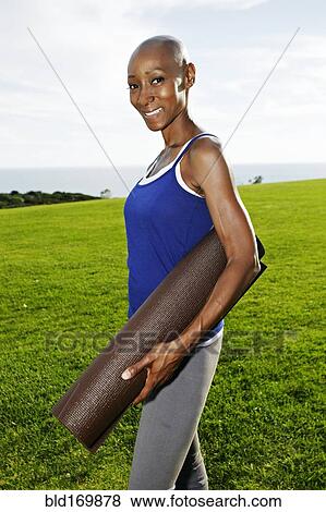 African American woman carrying yoga mat in park View Large Photo Image Stock Photo - African American woman carrying yoga mat in park. Fotosearch
