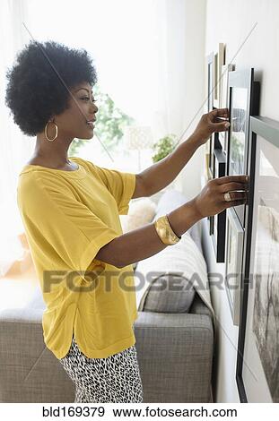 African American woman hanging pictures on living room wall View Large Photo Image Stock Photo - African American woman hanging pictures on living room wall. Fotosearch