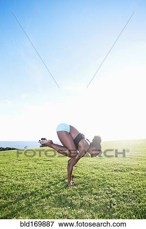 Stock Photo - African American woman practicing yoga in park. Fotosearch