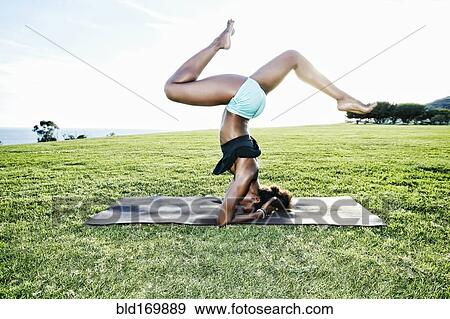 Stock Photo - African American woman practicing yoga in park. Fotosearch