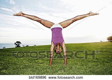 Stock Photograph - African American woman practicing yoga in park. Fotosearch