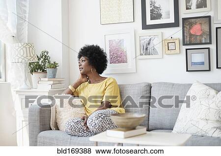Stock Photo - African American woman relaxing on sofa. Fotosearch