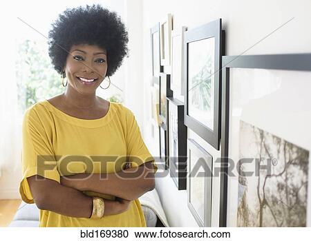 African American woman standing near pictures on wall View Large Photo Image Stock Image - African American woman standing near pictures on wall. Fotosearch
