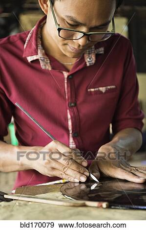 Stock Photo - Asian artisan carving traditional design in workshop. Fotosearch