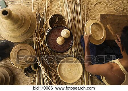 Stock Photograph - Asian artisan weaving traditional baskets in workshop. Fotosearch