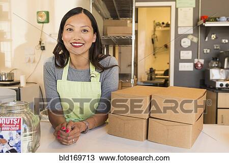Stock Image - Asian baker smiling in bakery. Fotosearch