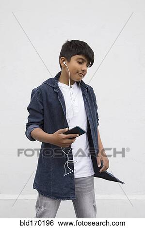 Stock Photograph - Asian boy listening to earbuds with cell phone. Fotosearch