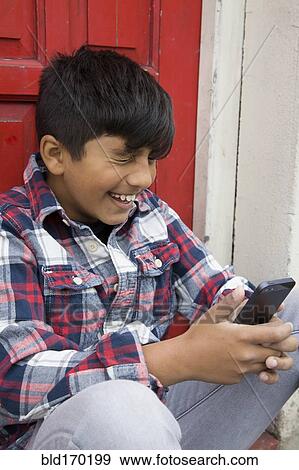 Asian boy using cell phone at door View Large Photo Image Stock Photo - Asian boy using cell phone at door. Fotosearch