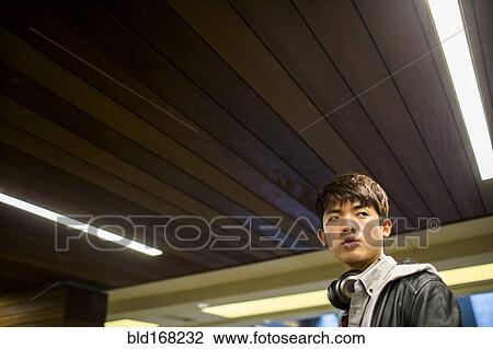 Stock Image - Asian man walking under wooden ceiling. Fotosearch