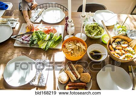 Stock Photo - Baby girl reaching for vegetables at buffet table. Fotosearch