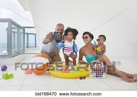 Stock Image - Black family taking selfie with swimming gear. Fotosearch