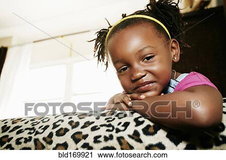 Stock Image - Black girl relaxing on sofa. Fotosearch