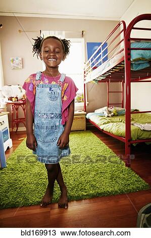 Stock Image - Black girl smiling in bedroom. Fotosearch