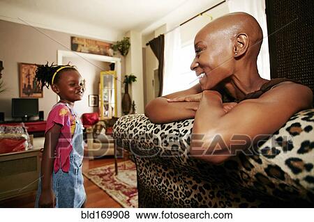 Stock Photo - Black mother and daughter smiling in living room. Fotosearch