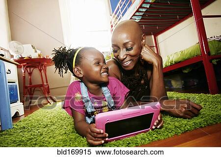 Black mother and daughter using digital tablet in bedroom View Large Photo Image Stock Photography - Black mother and daughter using digital tablet in bedroom. Fotosearch