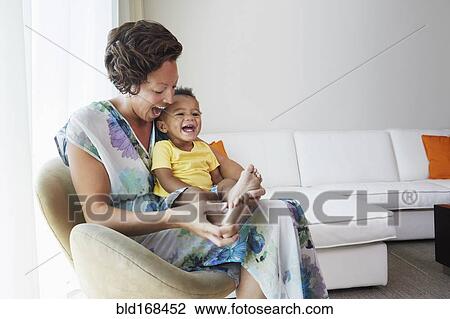 Stock Image - Black mother and son sitting in living room. Fotosearch