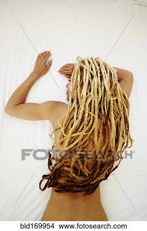 Picture - Black woman with dreadlocks laying on bed. Fotosearch