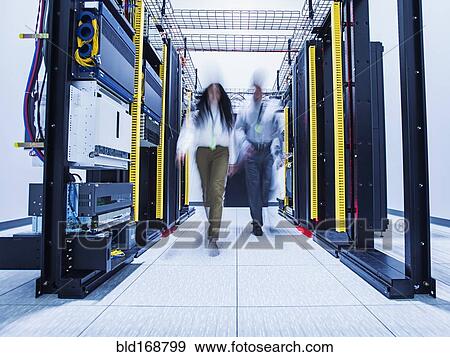 Stock Photo - Blurred view of technicians walking in server room. Fotosearch