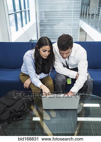 Stock Image - Business people using laptop in office lobby. Fotosearch