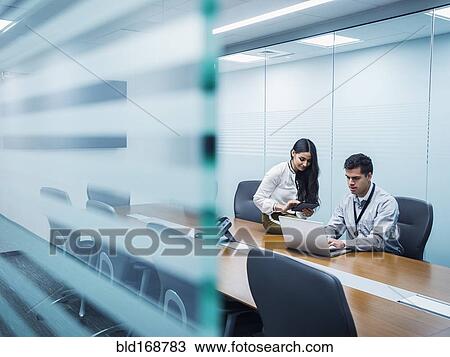 Stock Image - Business people using technology in conference room. Fotosearch