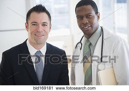 Stock Image - Businessman and doctor smiling in office. Fotosearch