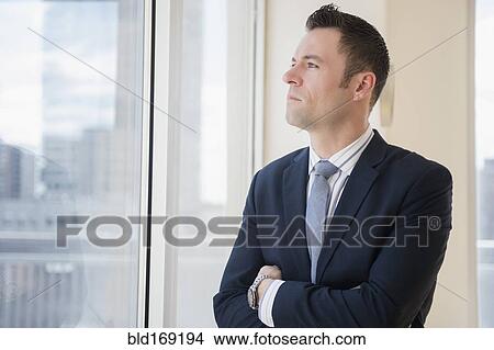 Businessman looking out office window View Large Photo Image Picture - Businessman looking out office window. Fotosearch