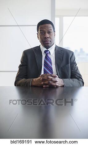 Stock Image - Businessman sitting at conference table in meeting. Fotosearch
