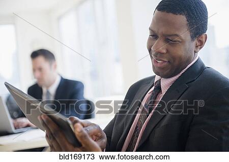 Stock Image - Businessman using digital tablet in office. Fotosearch