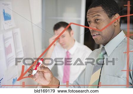 Businessman writing graph on glass wall in office View Large Photo Image Stock Photo - Businessman writing graph on glass wall in office. Fotosearch