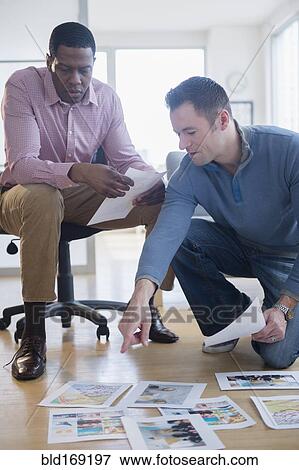 Businessmen examining paperwork on office floor View Large Photo Image Stock Photo - Businessmen examining paperwork on office floor. Fotosearch