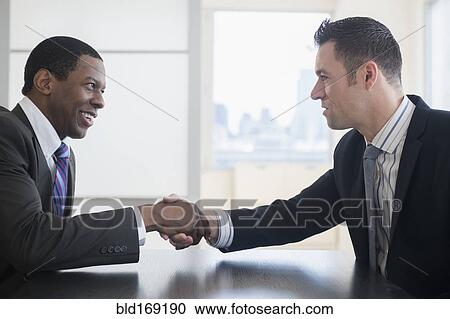 Businessmen shaking hands in office meeting View Large Photo Image Stock Image - Businessmen shaking hands in office meeting. Fotosearch