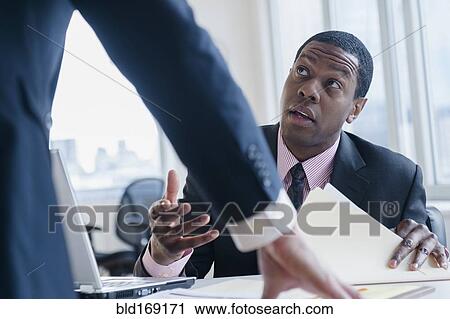 Stock Image - Businessmen talking at desk in office. Fotosearch