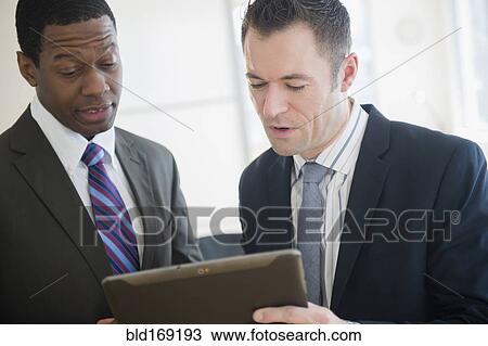 Stock Image - Businessmen using digital tablet in office. Fotosearch