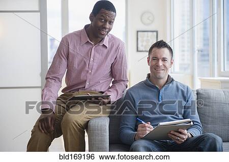 Stock Photograph - Businessmen with digital tablet and notepad on sofa. Fotosearch
