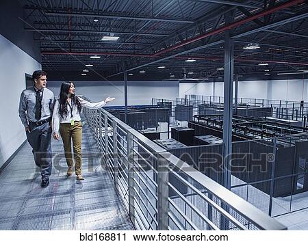 Stock Image - Businesswoman showing colleague server room from balcony. Fotosearch