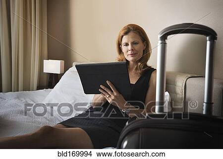 Picture - Businesswoman using digital tablet on hotel bed. Fotosearch