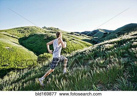 Stock Photo - Caucasian athlete running on rural hills. Fotosearch