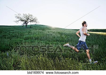 Picture - Caucasian athlete running on rural trail. Fotosearch