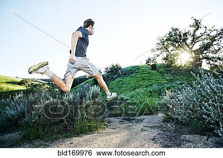 Stock Photograph - Caucasian athlete running on rural trail. Fotosearch