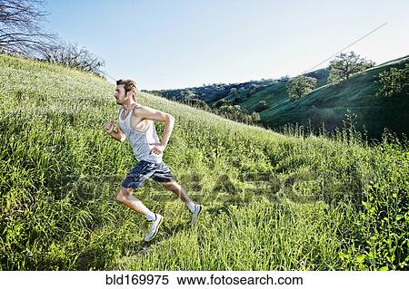 Stock Photography - Caucasian athlete running on rural trail. Fotosearch