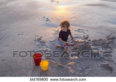 Stock Image - Caucasian baby boy playing on beach. Fotosearch
